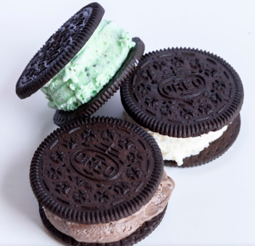 Three Oreo ice cream sandwiches with mint, vanilla, and chocolate filling stacked on a white background.