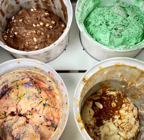 Four ice cream tubs with different flavors: chocolate, mint, rainbow sherbet, and caramel swirl.