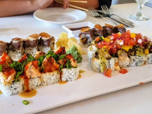 A platter of colorful sushi rolls with various toppings, accompanied by wasabi, ginger, and dipping sauce.