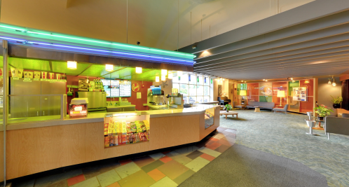 A brightly lit concession stand with snacks and drinks, surrounded by a cozy lounge area with seating.