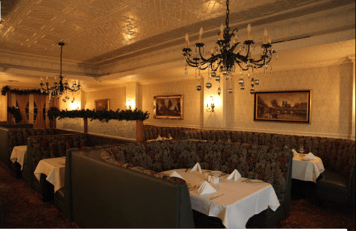 Elegant restaurant interior with plush booths, chandeliers, and festive decor, creating a cozy dining atmosphere.