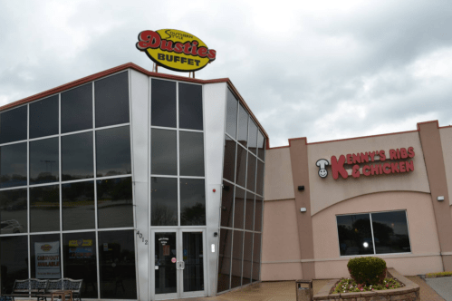 Exterior view of Dusties Buffet and Kenny's Ribs & Chicken, featuring large windows and a cloudy sky.