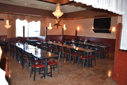 A spacious restaurant interior with rows of tables and chairs, elegant lighting, and a warm color scheme.