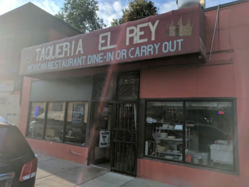 Exterior of Taqueria El Rey, a Mexican restaurant with a red facade, offering dine-in or carry-out options.