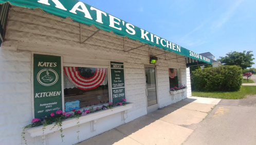 Exterior of Kate's Kitchen, featuring a green awning, patriotic decor, and flower boxes under the windows.