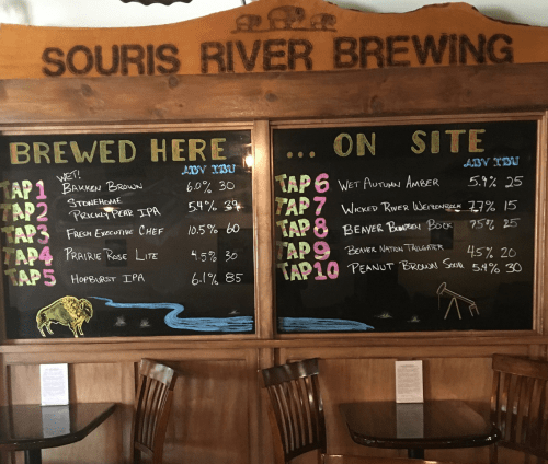 Chalkboard menu displaying Souris River Brewing's beer offerings and details, including names, ABV, and prices.