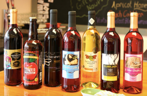 A variety of wine bottles displayed on a table, featuring different labels and colors, including reds and whites.