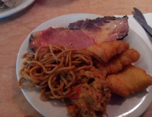 A plate with sliced roast beef, noodles, and two pieces of fried fish.