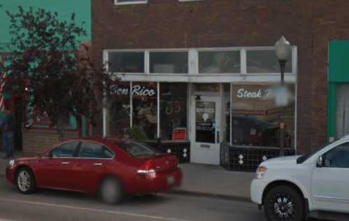 Exterior of Bon Rico Steak House with a red car parked outside and a brick building facade.