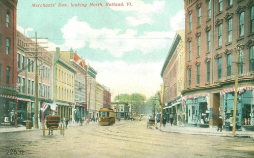 Historic view of Merchants' Row in Rutland, Vermont, featuring streetcars and storefronts on a sunny day.