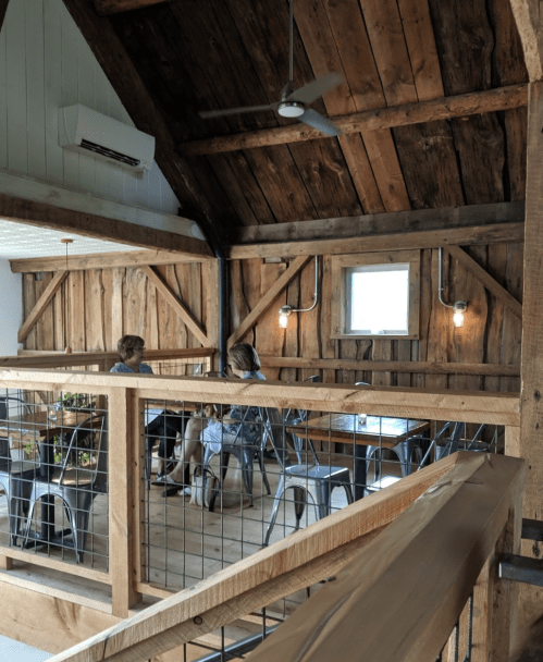 A cozy wooden interior of a café with two people seated at a table, surrounded by rustic decor and warm lighting.