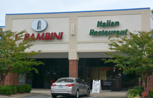Exterior of an Italian restaurant named "Rambini," featuring a sign and a parked car in front.