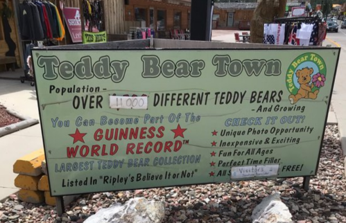 Sign for Teddy Bear Town, promoting over 11,000 teddy bears and Guinness World Record collection. Family-friendly attraction.