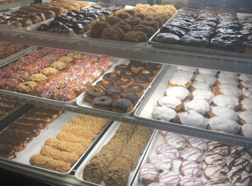 A display case filled with various donuts, including glazed, chocolate, and sprinkled varieties.