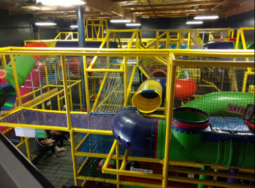 Colorful indoor play structure with slides and climbing areas, filled with nets and tunnels for children to explore.