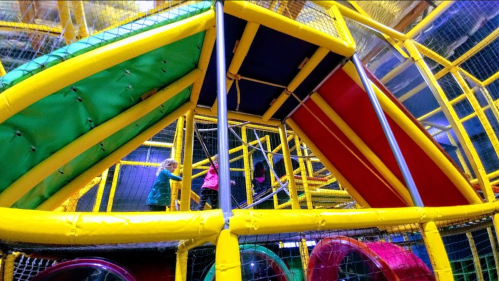 Colorful indoor play structure with slides and climbing areas, children playing and exploring inside.