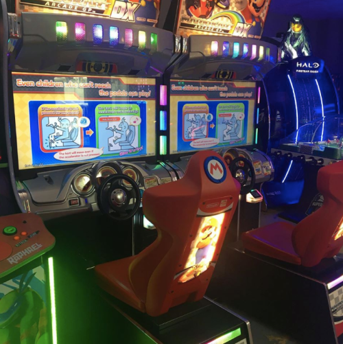 Two arcade racing games with colorful screens and seats, featuring instructions for gameplay and a vibrant gaming environment.