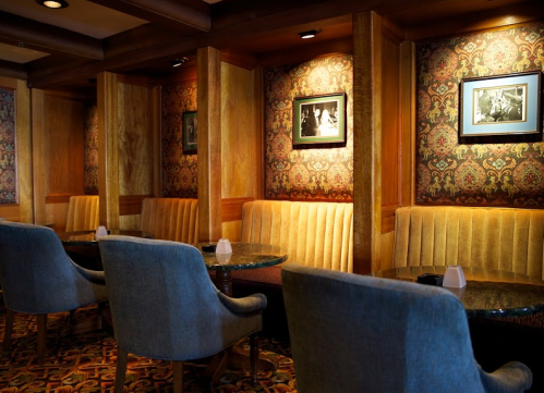 Cozy café interior with plush seating, patterned wallpaper, and framed black-and-white photos on the walls.