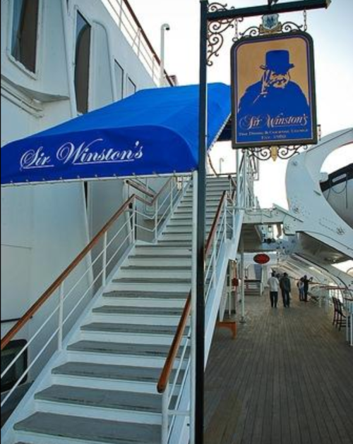 Stairs leading to Sir Winston's restaurant, with a blue awning and a sign, on a ship's deck.