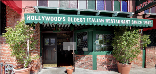 Exterior of a historic Italian restaurant in Hollywood, featuring a green awning and brick facade.
