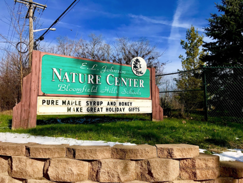 Sign for E.L. Johnson Nature Center, promoting pure maple syrup and honey as great holiday gifts.