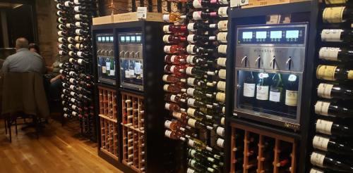 A wine display featuring multiple bottles on shelves and a wine dispensing machine in a cozy setting.