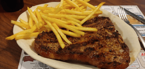 A plate featuring a grilled steak alongside a generous serving of golden French fries.