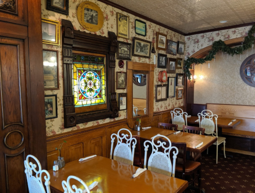 Cozy restaurant interior with wooden accents, vintage decor, and a colorful stained glass window.