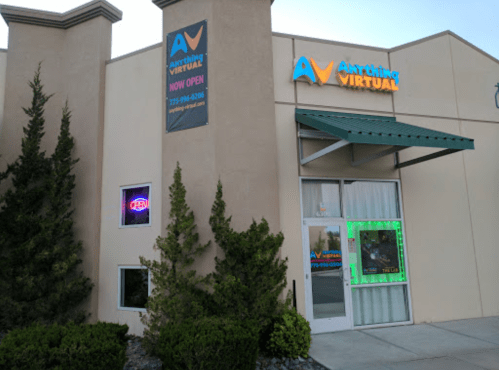 Exterior of a building with a sign for "Anything Virtual," featuring an open neon sign and green-lit entrance.