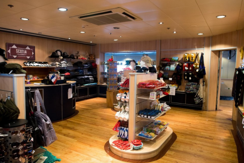 A brightly lit store interior featuring shelves of clothing, accessories, and souvenirs in a wooden setting.