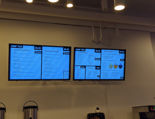 Digital menu boards displaying various tea options and prices in a cafe setting.