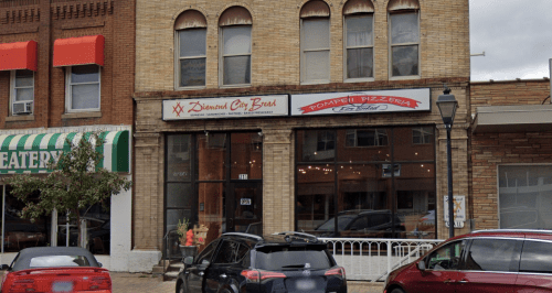 Exterior view of a brick building featuring "Diamonds Car Bros" and "Pompeii Pizzeria" signs, with parked cars in front.