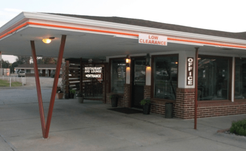Exterior view of a restaurant and lounge entrance with a low clearance sign and a brick facade.