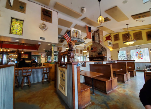 Interior of a cozy restaurant featuring wooden seating, colorful wall art, and decorative flags.