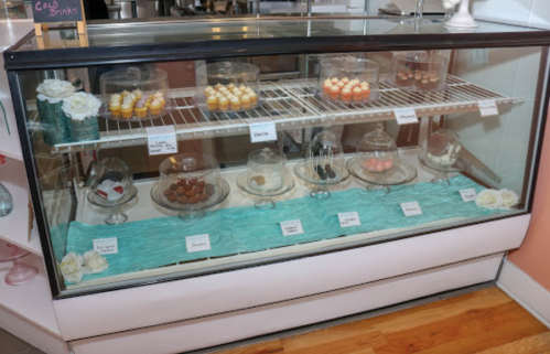A display case filled with various desserts, including cupcakes and candies, on a turquoise cloth.