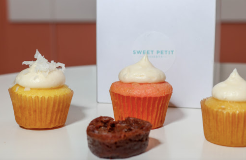 Three colorful cupcakes on a table, with a box labeled "Sweet Petit" in the background.