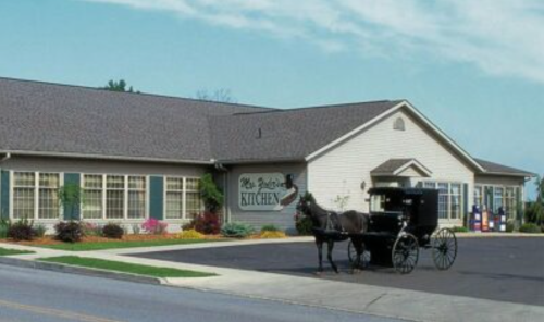 A horse-drawn carriage in front of a quaint restaurant with a sign reading "The Pigeon Kitchen."