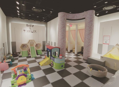 Bright playroom for babies and toddlers, featuring colorful toys, play structures, and soft flooring.