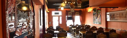 Interior of a cozy restaurant featuring ornate decor, wooden tables, and warm lighting.