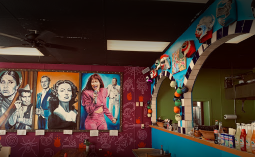 Colorful restaurant interior featuring vibrant murals of iconic figures and playful decor on the walls.