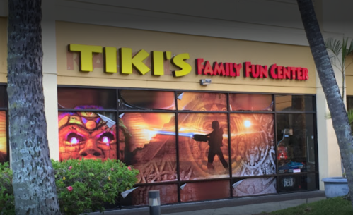 Exterior of Tiki's Family Fun Center, featuring colorful signage and vibrant window graphics depicting fun activities.