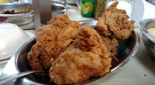 A close-up of crispy fried chicken pieces served in a metal dish.
