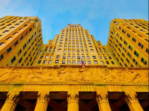 View of a tall, historic building with intricate carvings and a clear blue sky above.