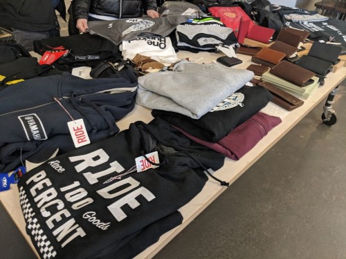 A table displaying various clothing items, including hoodies and shirts, alongside wallets and accessories.