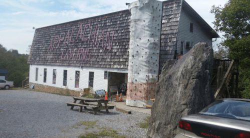 A large building with "Appalachian Climbing" signage, featuring a rock climbing wall and a picnic area outside.