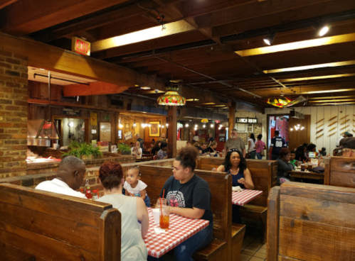 A bustling restaurant interior with wooden booths, diners enjoying meals, and warm lighting.