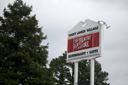 Sign for Casey Jones Village featuring "Old Country Store" and "Restaurant & Gifts" against a cloudy sky.
