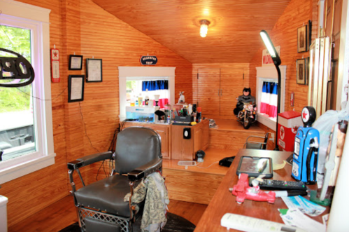 A cozy barbershop interior with wooden walls, a barber chair, and various grooming supplies on a counter.