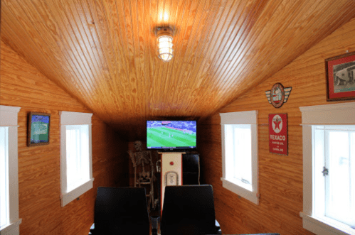 Cozy room with wooden walls, a TV showing a soccer game, and vintage decor, including a Texaco sign.