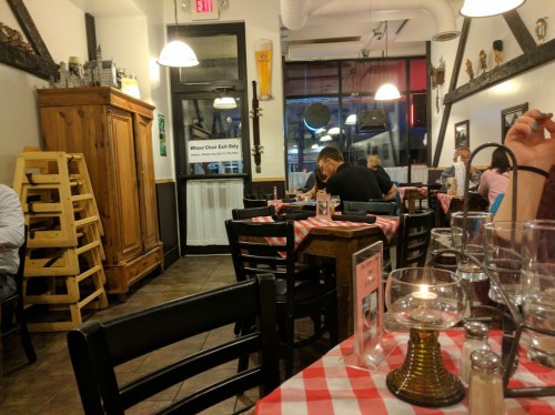 A cozy restaurant interior with checkered tablecloths, wooden furniture, and a warm ambiance.